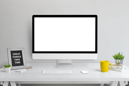 Computer display mockup. Web design presentation template. Modern studio work desk with plant, picture frame, keyboard, mouse, coffee mug and books.