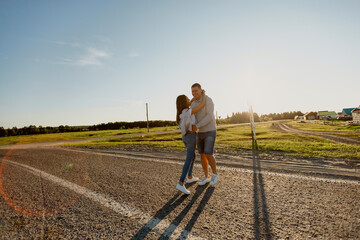 Portrait of a couple in love walking along the road. A man and a woman enjoy a vacation in the countryside. Young people walk in nature.