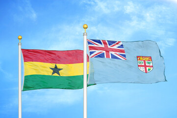 Ghana and Fiji two flags on flagpoles and blue sky