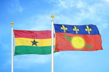 Ghana and Guadeloupe two flags on flagpoles and blue sky