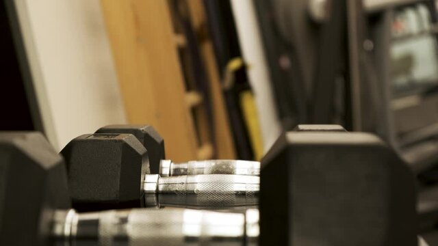 Closeup of veiny hand taking dumbbells from weight rack. strength training equipment in gym. Muscle built body builder athlete

