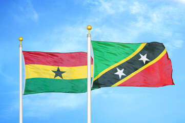 Ghana and Saint Kitts and Nevis two flags on flagpoles and blue sky
