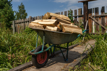 A garden cart with chopped wood stands on a wooden bridge.