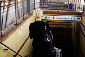 Frau mit Koffer auf Bahnsteig
