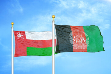 Oman and Afghanistan two flags on flagpoles and blue sky