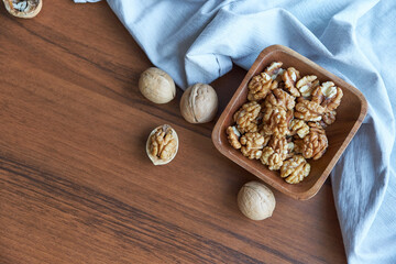 Walnuts kernels on dark desk with color background, Whole walnut in wood vintage bowl.