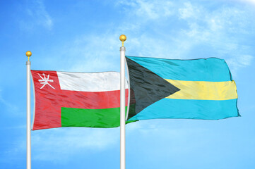 Oman and Bahamas two flags on flagpoles and blue sky