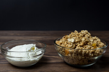 granola in a transparent bowl with pieces of tropical fruits and a bowl of yogurt