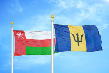 Oman and Barbados two flags on flagpoles and blue sky
