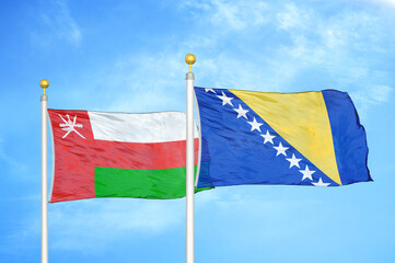 Oman and Bosnia and Herzegovina two flags on flagpoles and blue sky