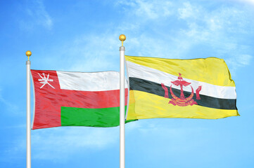 Oman and Brunei two flags on flagpoles and blue sky