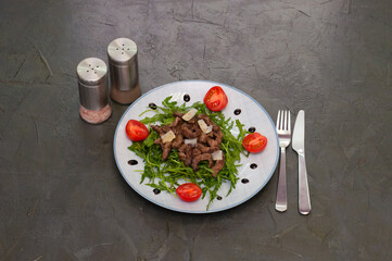 Tasty and juicy grilled meat arugula, cheese, tomato sauce and spices on a dark gray concrete background, top view