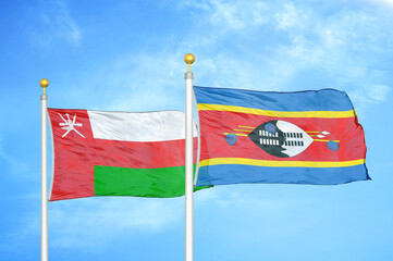 Oman and Eswatini Swaziland two flags on flagpoles and blue sky