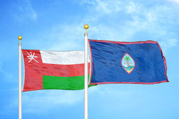 Oman and Guam two flags on flagpoles and blue sky