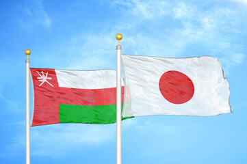 Fototapeta na wymiar Oman and Japan two flags on flagpoles and blue sky