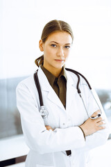 Woman-doctor standing with arms crossed and looking at camera. Perfect medical service in clinic