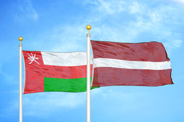 Naklejka na ściany i meble Oman and Latvia two flags on flagpoles and blue sky