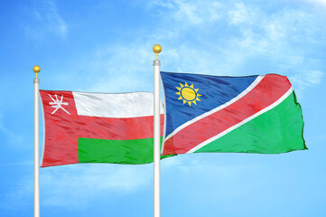 Fototapeta na wymiar Oman and Namibia two flags on flagpoles and blue sky