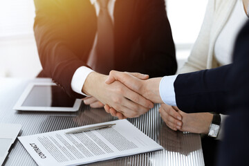 Business people shaking hands after contract signing in sunny modern office. Teamwork and handshake concept