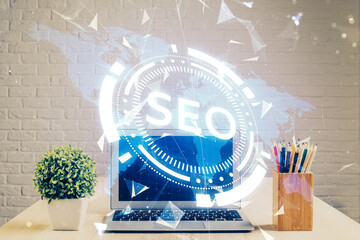 Double exposure of table with computer and seo drawing hologram. Search optimization concept.