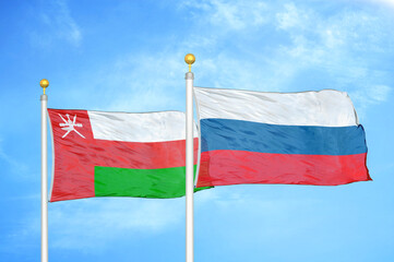 Oman and Russia two flags on flagpoles and blue sky