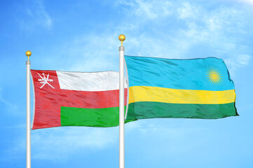 Oman and Rwanda two flags on flagpoles and blue sky