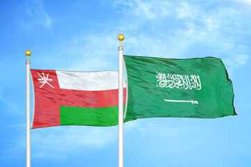 Oman and Saudi Arabia two flags on flagpoles and blue sky