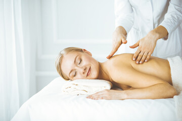 Fototapeta na wymiar Beautiful happy woman enjoying back massage with closed eyes. Beauty and Spa salon concept