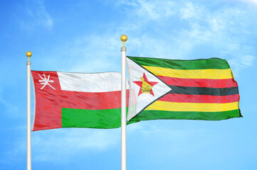Oman and Zimbabwe two flags on flagpoles and blue sky