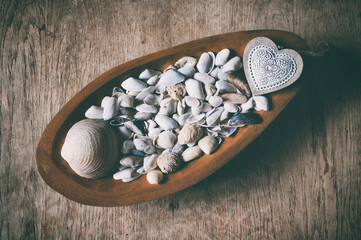 Still life with seashells in a wooden bowl on an old cracked table - 368739929
