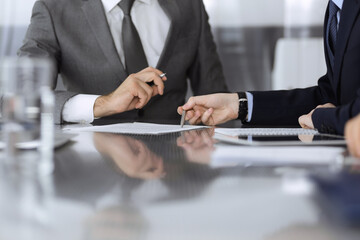 Unknown business people working together at meeting in modern office, close-up. Businessman and woman with colleagues or lawyers discussing contract at negotiation