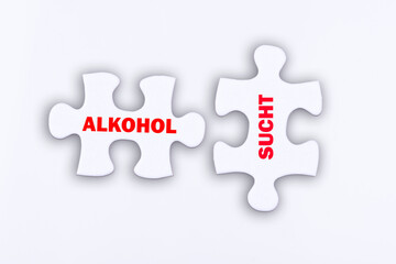 Zwei Puzzle Teile mit den Schlagwörtern Alkohol und Sucht