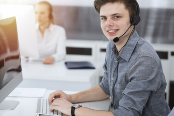 Call center. Group of casual dressed operators at work. Businessman in headset at customer service office. Telesales in business