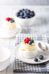 Delicious dessert Pavlova cake with whipped cream and fresh berries on white plate
