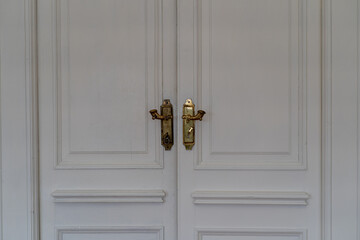 Close-Up Of A White Closed double Door. Gold-plated Door handles on the door