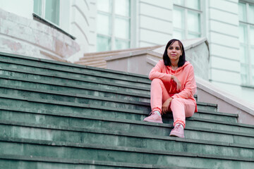 Fototapeta premium Young woman poses on stairs of manor. Adult female sitting on steps of Palace.