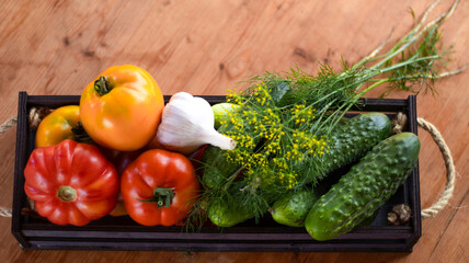 Vegetables tomatoes and cucumbers in a wooden box on a wooden table, close-up. Harvest, garden, vegetable garden. Blurred bokeh background.