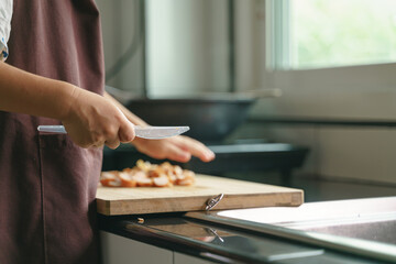 Asian boy cooking by cutting sausage