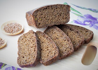 Composition in daylight. Slices of homemade rye bread on a wooden board, against the background of a colored tablecloth
