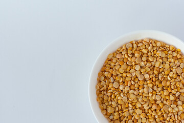 Cooked chick peas in a white ceramic bowl isolated on white. Spilled chick peas. Top view