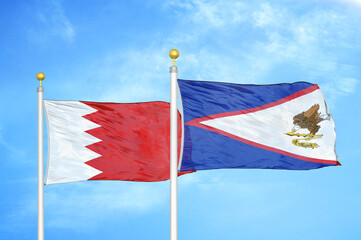 Bahrain and American Samoa two flags on flagpoles and blue sky