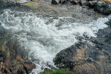 Full frame nature background of water riffle of mountain river. Powerful water stream of mountain creek with rapids. Natural textured backdrop of fast flow of mountain brook. Rapids texture close-up.