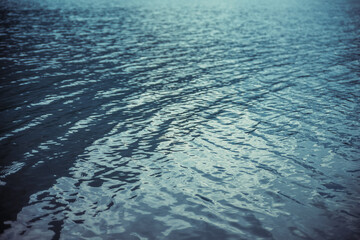Texture of purple calm water of mountain lake. Meditative ripples on water surface. Nature minimal background of violet lake. Natural backdrop of clear dark blue water. Full frame of lake fragment.