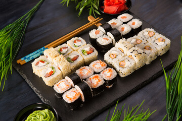 Set of sushi rolls with wasabi and ginger on black background. Japanese oriental cuisine