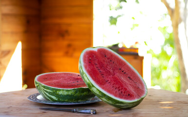 Watermelon in a rustic wooden gazebo on a wooden table. A large red watermelon cut in half. Summer...
