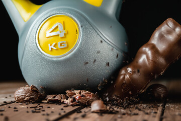 Heavy kettlebell crushing Easter chocolate eggs and bunny on wooden table.