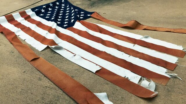 4K footage of a tattered American flag lying on the ground