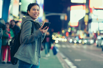 asian female traveller smile happiness hand hold mirrorless camera enjoy nightlife lifestyle tourost with light bokeh and crowd of people blur background in winter season