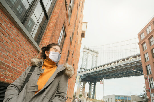 Asian Attractive Woman Traveller Wearing A Face Pollution Mask To Protect Herself From The Coronavirus With Background Of Down Under The Manhattan Bridge Overpass Near The Manhattan Bridge Newyork US