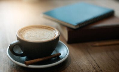Close up and soft focus of coffee in ceramic cup with old book on wooden table, Vintage color tone